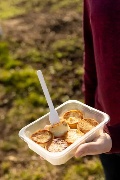 Açık hava beslenme çantasından peynirli krep yiyen bir adam. Atıştırmalık temiz hava. Sağlıklı düşük kalorili yiyecekler. Güneşli bir günde abur cubur. süzme peynirli krep.