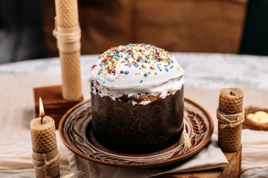 Paskalya pastası, paskalya ekmeği, beyaz jöleli paskalya ekmeği, paskalya pastası renkli pudra, mum mumları, sıcak atmosfer.