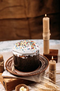 Paskalya pastası, paskalya ekmeği, beyaz jöleli paskalya ekmeği, paskalya pastası renkli pudra, mum mumları, sıcak atmosfer.