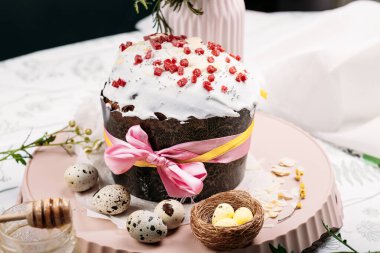 Paskalya pastası, ballı Paskalya ekmeği, beyaz jöleli ve donuk meyvelerle kaplı hafif bir arka planda, mumlar yakında yanıyor. Paskalya konsepti