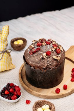 Paskalya pastası, çikolata jöleli paskalya ekmeği kuru kiraz ve cevizle süslenmiş arka planda uzun mumlar, çiçekler, yakınlarda Paskalya tavşanı. Paskalya konsepti