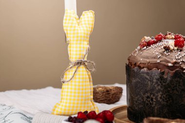 Paskalya pastası, paskalya pastası, çikolata kaplı paskalya ekmeği kuru kiraz ve cevizle süslenmiş hafif arka plan, uzun mumlar, yakında çiçekler. Paskalya konsepti