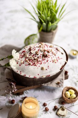 Paskalya pastası, ballı Paskalya ekmeği, beyaz jöleli ve dondurulmuş böğürtlenlerle kaplı hafif bir arka planda, mumlar yakında yanıyor. Paskalya konsepti