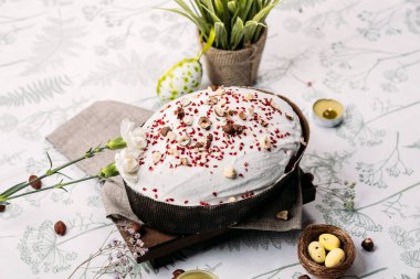 Paskalya pastası, ballı Paskalya ekmeği, beyaz jöleli ve dondurulmuş böğürtlenlerle kaplı hafif bir arka planda, mumlar yakında yanıyor. Paskalya konsepti