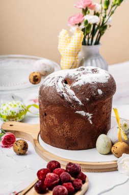 Seramik bir stantta, renkli bıldırcın yumurtaları, vazodaki pembe ve beyaz çiçeklerin yanında, neşeli bir atmosferde paskalya kabuğu. Paskalya konsepti