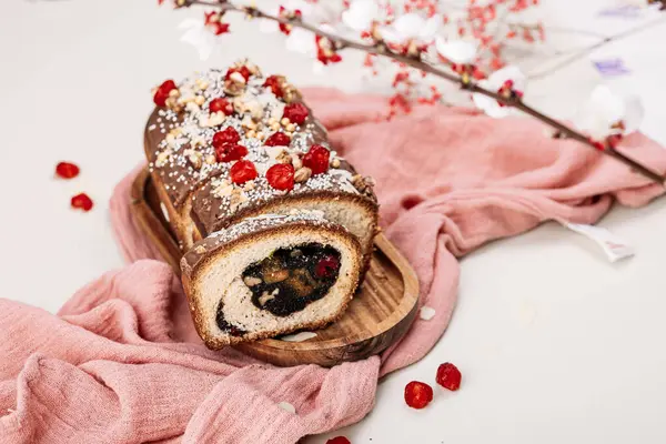 Paskalya ekmeği, haşhaş tohumu dolgulu panettone, fındık, kuru kiraz, açık arkaplanda pembe bir peçetede çikolata jöleli kuru üzüm. Paskalya konsepti