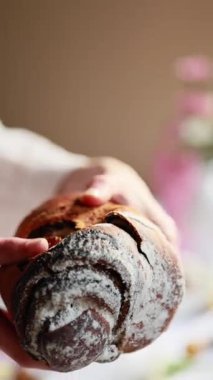 Bir kadın haşhaş tohumu dolgulu yumuşak bir hamur göstererek kabuk kırar. Haşhaş tohumlu kabuk. Paskalya ekmeği. Paskalya yumurtaları ve bahar çiçekleri