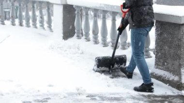 Kürekli adam karı temizler. Kar fırtınasından sonra evin yakınındaki bölgeyi temizliyorum. Yoldan kar kürüyen bir adam. Büyük kar yığınları. Kar fırtınası sonrası şehirde zor bir durum.