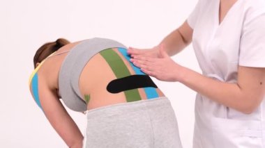 Young woman with kinesio tape on her back and sides. Kinesio taping for lifting a bulging abdomen and side. Weight loss on white background