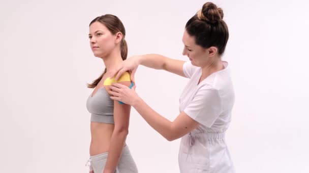 Skulderbehandling Med Kinesiobånd Fysioterapeut Anvender Elastisk Terapeutisk Tape Til Patientens – Stock-video