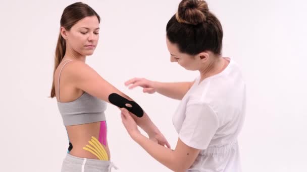 Closeup Doctor Fixing Kinesio Tape Womans Elbow Rehabilitation Process White — Vídeo de stock