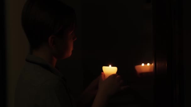 少年坐在黑暗中 手里拿着蜡烛 窗上有倒影 被遗弃的城堡概念 — 图库视频影像