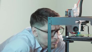 Gözlük takan mühendis, yeşil plastiğin üç boyutlu yazıcıdaki dişli detaylarını izliyor. Modern tasarım teknolojisi kavramı
