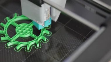 3D yazıcı yeşil plastikten bir dişli basıyor. Masaüstünde yeni bir ayrıntı katman katman görünür. Modern tasarım teknolojisi kavramı