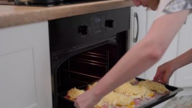 Modern mutfakta et ve peyniri fırına koyan kadın et yemeği yapıyor. Gıda hazırlama süreci