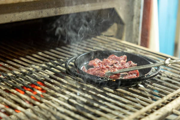 Diced beef cubes roasting in a grill pan for stew or goulash. a frying pan with meat is cooked on a professional grill. Cooking in a restaurant