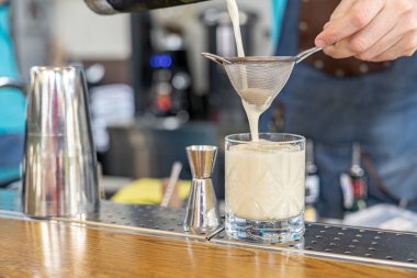 Barmen kokteyl hazırlıyor. Barmen süzgeçten bir kokteyl döktü.