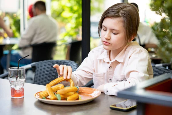 stock image Portrait of teenager boy eating french churros in the outdoor summer cafe