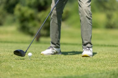Golf sahası yeşil. Golfçü golf sahasında topa vuruyor.