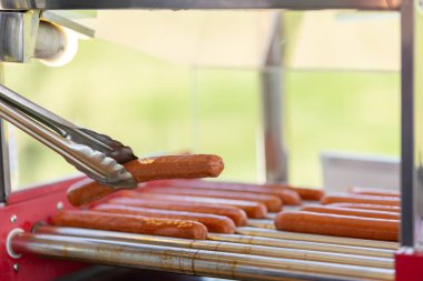 Bir kafedeki mutfak makinesinde yağlı sosisler. Arka planda susamlı sosisli sandviç ekmeği için sosis pişiriyorum. Geleneksel Amerikan fast food.