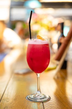 Barda turuncu ve buzlu pembe ve kırmızı renkli egzotik alkollü kokteyl. Barın masasında buzlu, renkli, pembe bir içecek. Kırmızı renkli Mojito.