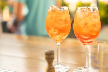 Güneşli restoran arka planında iki aperol spreyli içecek yakın. Boşluğu kopyala