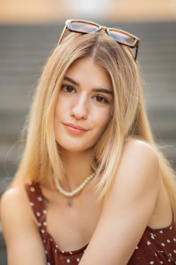 Parkta gülümseyen genç sarışın kadın portresi.