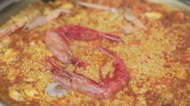 Yazın açık hava gıda pazarında karides, pirinç, baharat ve safranla paella pişirme süreci: Kapatın. İspanyol mutfağı, deniz ürünleri, gastronomi, sokak yemekleri konsepti.