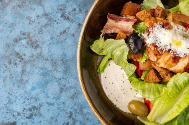 Mavi gri taştan arka planda Sezar Salatası, üst manzara, kopyalama alanı. Kızarmış ekmek arası tavuklu sezar salatası. Restoran servisi