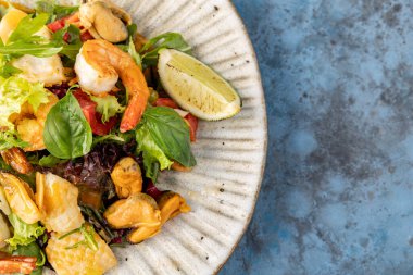 Midyeli salata, karides, gri-mavi arka planda limon. Mesaj için yer. en üstteki görünüm