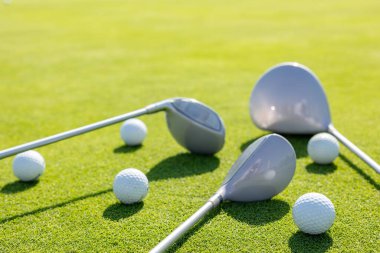 Golf sopaları ve toplar yeşil çimlerin üzerinde..