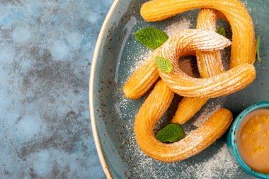 Çuro, ahşap bir tahtanın üzerinde krema şekeri ile süslenmiş İspanyol tatlısı. Gri desenli arka plan. Güzel servis tabakları. Tatlı. Besin zinciri