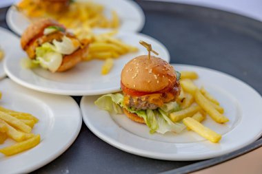 Çocuklar için düzenlenen yemek organizasyonunda kızarmış hamburgerle mini hamburgerleri yakın..