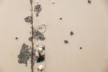 Chernihiv bölgesi. Rus işgali Ukrayna 'da. Konut binasının metal kapısında kurşun delikleri var. Bombardıman ve ateş izleri. Kapıda bir demet çiçek..