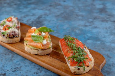 Tahta bir kesme tahtasının üzerinde çeşit çeşit bruschetta. İtalyan mutfağı.