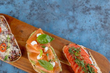 Tahta bir kesme tahtasının üzerinde çeşit çeşit bruschetta. İtalyan mutfağı.