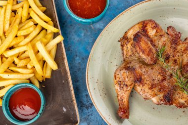 Izgara kızarmış tavuk Tabaka, patates kızartması ve mavi arka planda ketçap. Üst görünüm