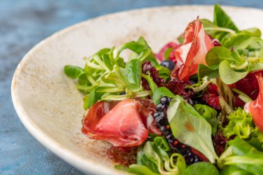 Jambonlu ve dutlu lezzetli salata. Tabakta yaz salatası. Mavi arkaplan