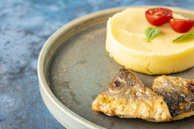 Kızarmış deniz balığı filetosu ve masaya yakın bir tabakta patates püresi. Restoran servisi. Mesaj için yer. Çocuk menüsü