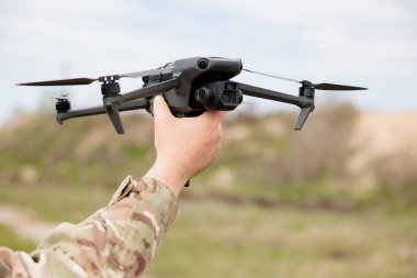 Bir asker elinde bir İHA tutuyor. Quadcopter başlatılıyor.
