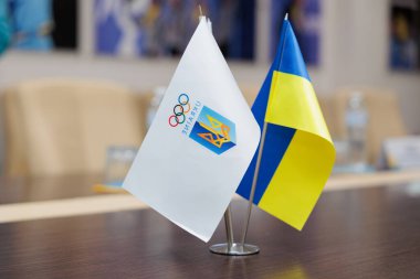Bir konferans veya iş toplantısında Ukrayna bayrağı ve Olimpiyat Komitesi bayrağı masada duruyor