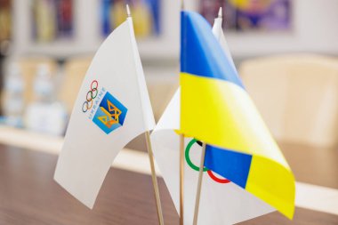 Bir konferans veya iş toplantısında Ukrayna bayrağı ve Olimpiyat Komitesi bayrağı masada duruyor