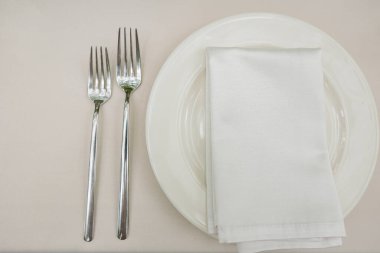 Eski beyaz masa üzerinde çatal ve peçete ile boş tabak, üst görünüm