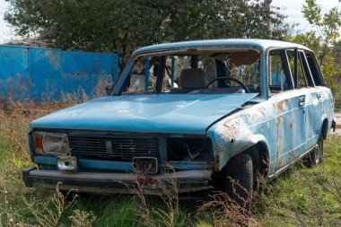 Ukrayna 'da savaş. 2022 Rus istilası Ukrayna. Kırsal kesimde. Yıkılmış bir sivil araba yolun kenarında duruyor. Arabanın gövdesinde kurşun delikleri ve kıymıklar var.