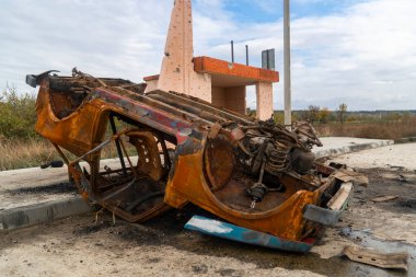 Ukrayna 'da savaş. 2022 Rus istilası Ukrayna. Kırsal kesimde. Bir otobüs durağında devrilmiş bir sivil araba yatıyor. İnsan yok. Savaş Suçları