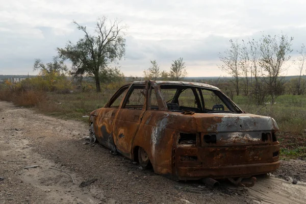 stock image War in Ukraine. 2022 Russian invasion of Ukraine. Countryside. A destroyed burnt-out civilian car stands on the side of the road. No people. War crimes