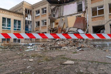 Ukrayna 'da savaş. 2022 Rus istilası Ukrayna. Okul bombardımandan sonra hasar gördü. Ön planda bir uyarı bandı gerildi. Altyapı tahribatı