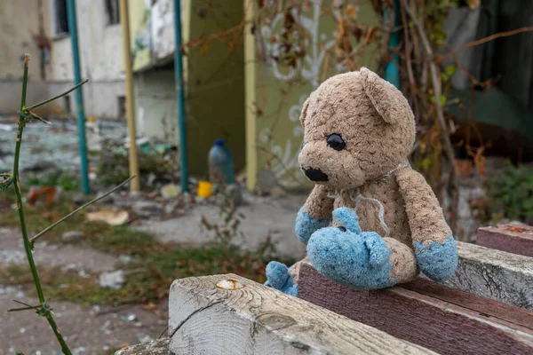 stock image War in Ukraine. 2022 Russian invasion of Ukraine. hildren's toy (teddy bear) lies against the backdrop of an apartment building destroyed by shelling. Terror of the civilian population. War crimes