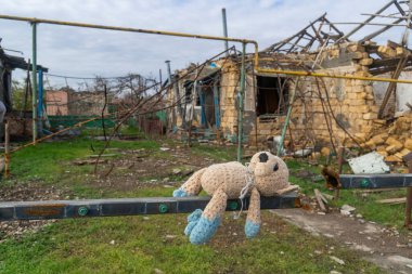 Ukrayna 'da savaş. 2022 Rus istilası Ukrayna. Kırsal kesimde. Bir oyuncak (oyuncak ayı) bombardımanla yıkılan bir evin arka planına karşı. Sivil halkın terörü. Savaş Suçları