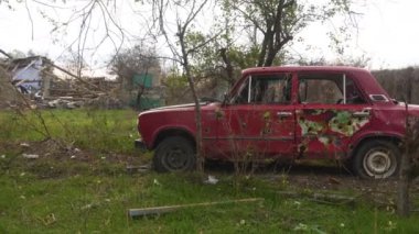 Ukrayna 'da savaş. 2022 Rus istilası Ukrayna. Kırsal kesimde. Yolun kenarında mahvolmuş, yanmış bir sivil araba var. Savaş suçları. Panorama. Kamera soldan sağa hareket ediyor.